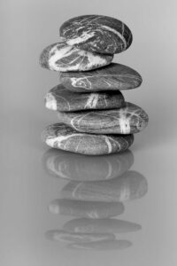 The cairn of balanced stones that resembles the Scippa & Associates logo icon with reflection