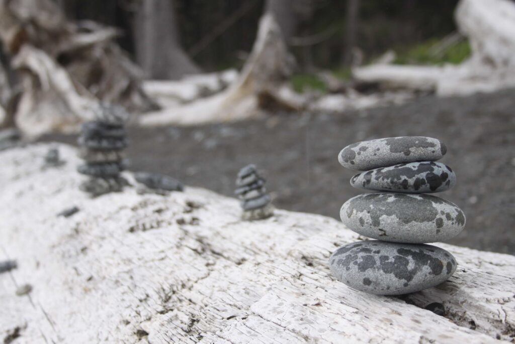 Rocks with raindrops stacked in a Cairn on a log.
