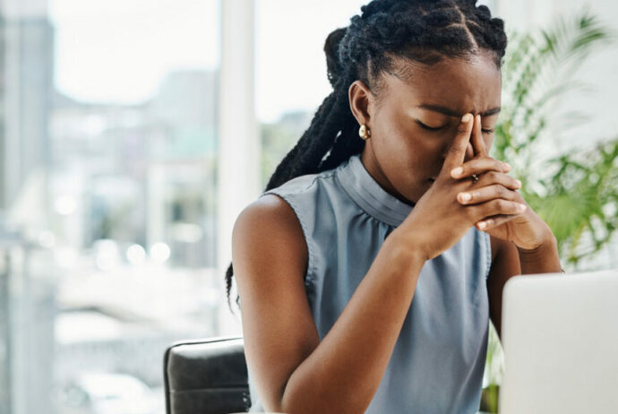 African American business person sitting at laptop with stressed expression.