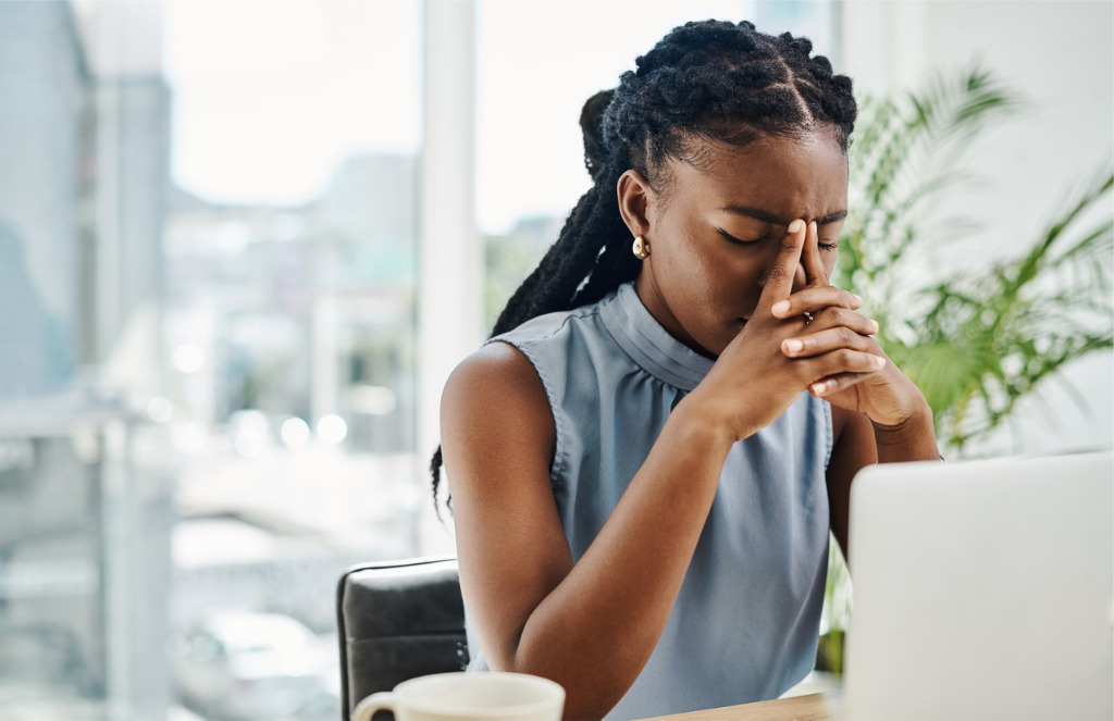 African American business person sitting at laptop with stressed expression.